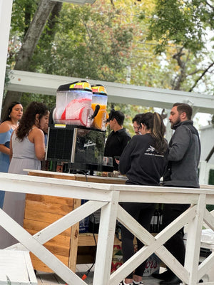 Bartenders serving margaritas from Los Weekenders to a line of people at a wedding