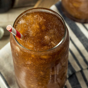 Coke and rum frozen drink mix in cup sitting on table